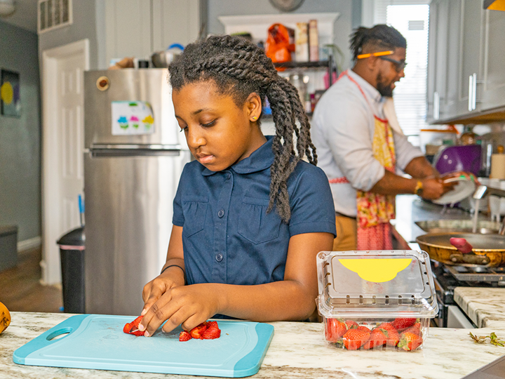 Dad and young girl preparing food in a kitchen