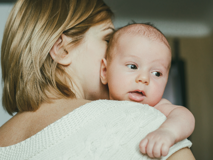 A woman with her back to the camera holding her baby
