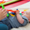 Baby lying on their back on a mat playing with a multi-coloured string toy