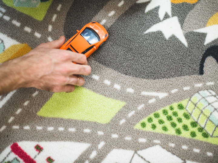 Toy Carpet Map With A Man's Hand Holding A Toy Orange Car