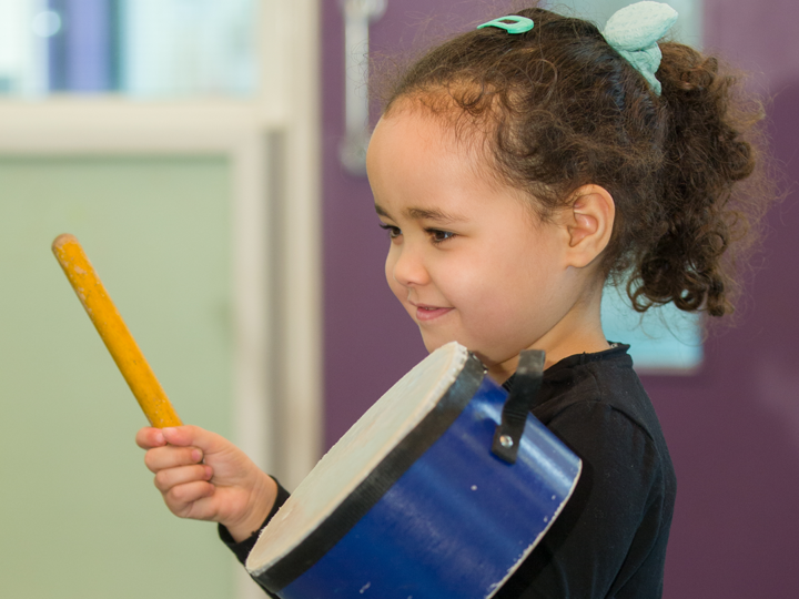 Child playing with drum and drumstick