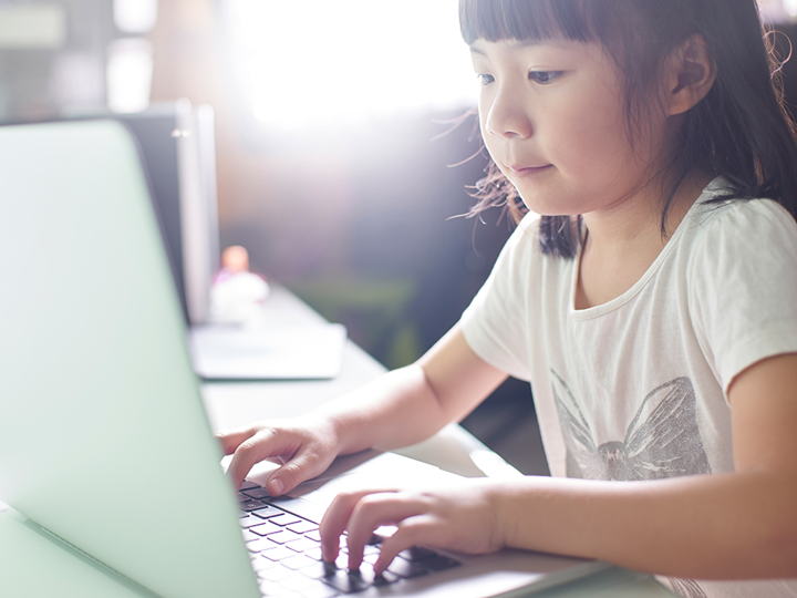 child typing on laptop