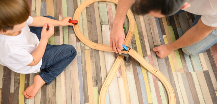Man And Young Boy Playing With Toy Cars On A Track