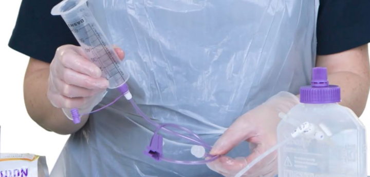 Healthcare worker in scrubs holding feeding equipment