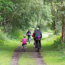 Family cycling down a grass track through a woodland area.