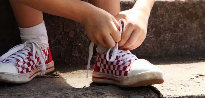 Young boy sitting on steps tying shoelace