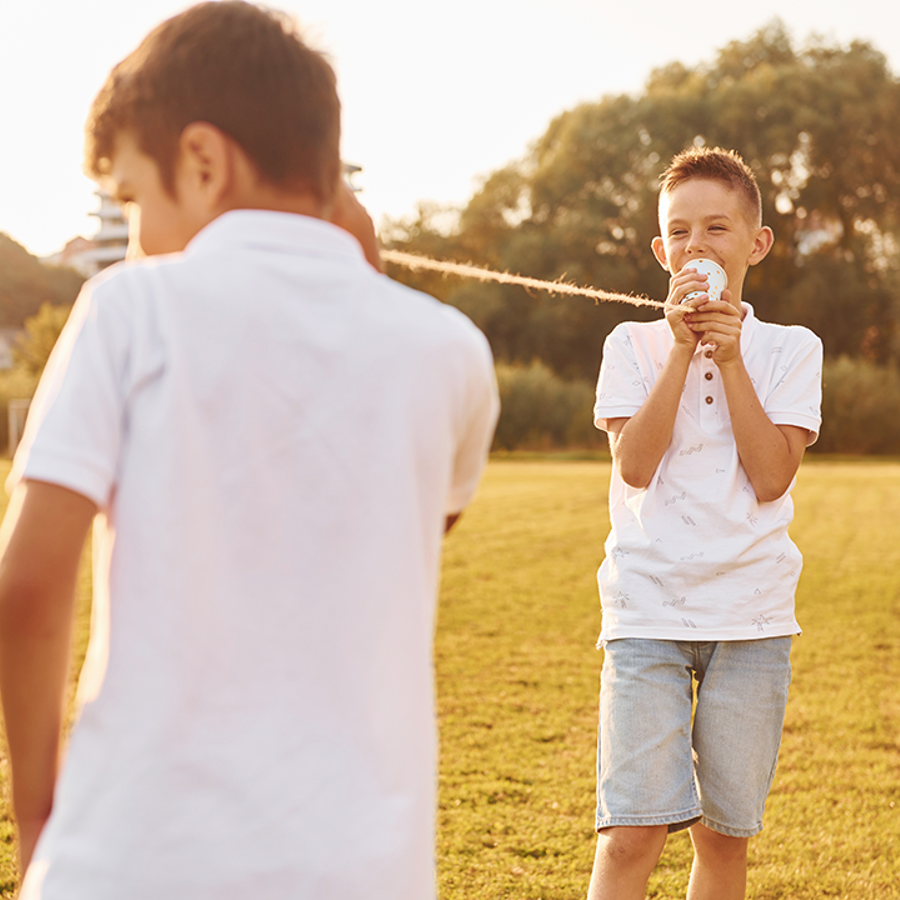 2 boys playing with a cup and string telephone toy 