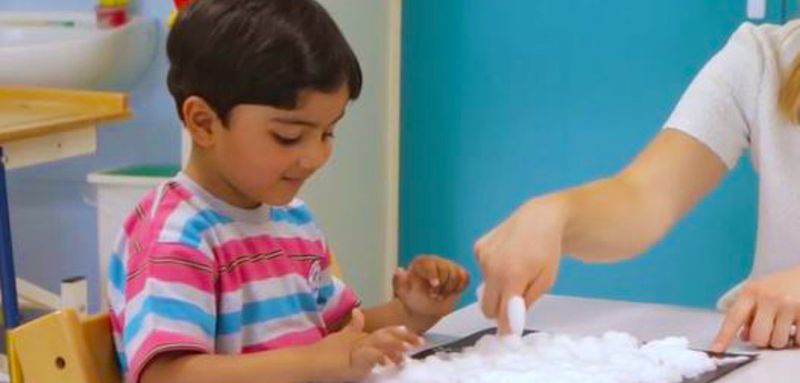 Child sat a table playing with bubbles
