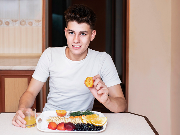 Teenage Boy With A Plate Of Fruit And A Glass Of Orange Juice