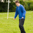 Boy in school uniform standing in a school field about to kick a football.