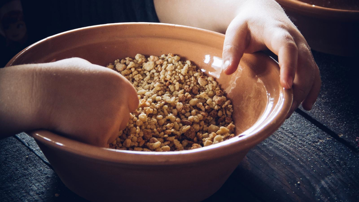 Child Putting Hand Into Bowl Of Dry Cereal (1)