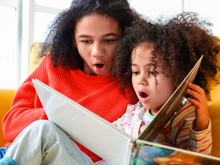 Adult And Child Reading Book Together With Mildly Shocked Expression