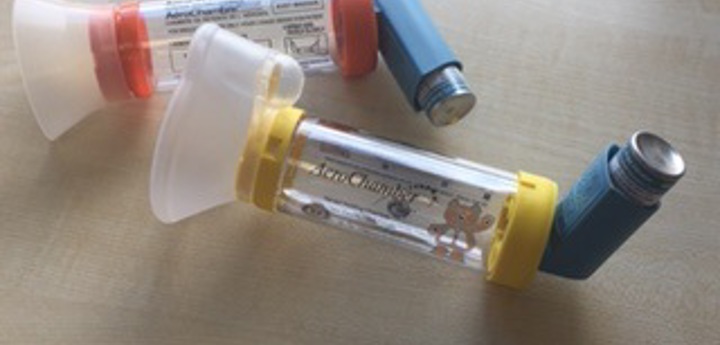 2 aero chambers with inhalers inserted in both of them lying on a table