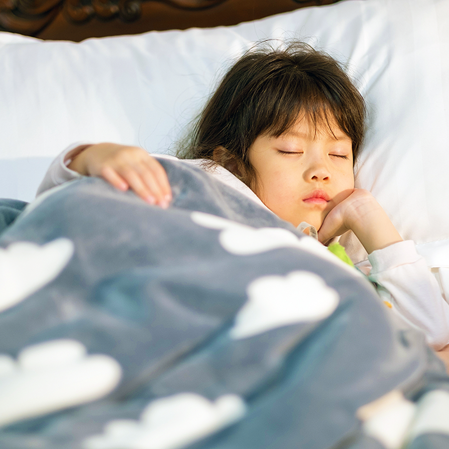 child sleeping in bed with cloud blanket
