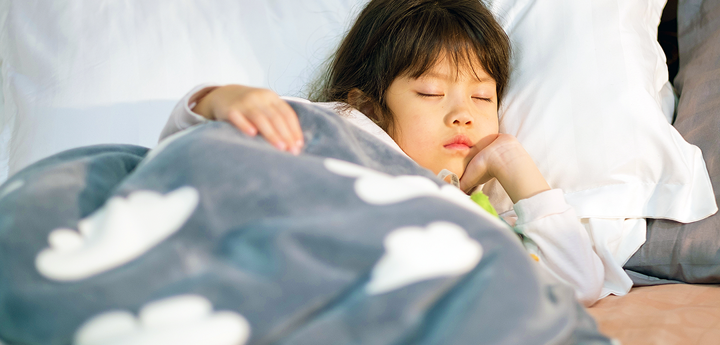 child sleeping in bed with cloud blanket