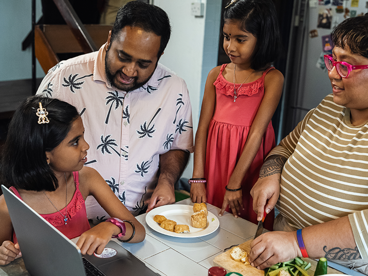Family Preparing Food Around Laptop