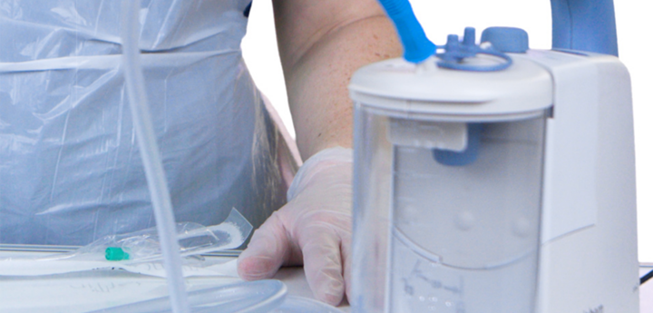 Suctioning equipment with person in scrubs standing behind it