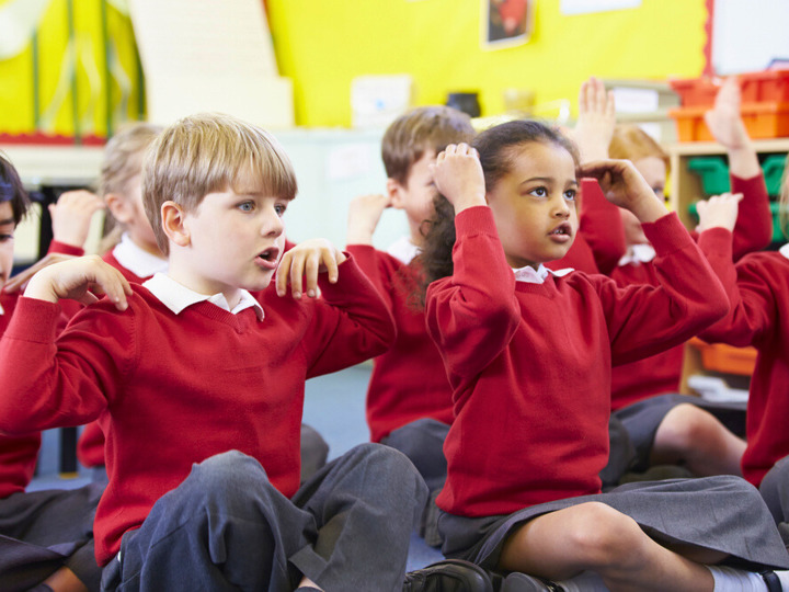 Children In Classroom Sitting And Singing Songs With Actions