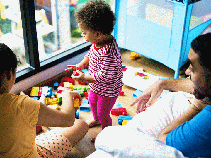 child standing playing with toys with parents watching