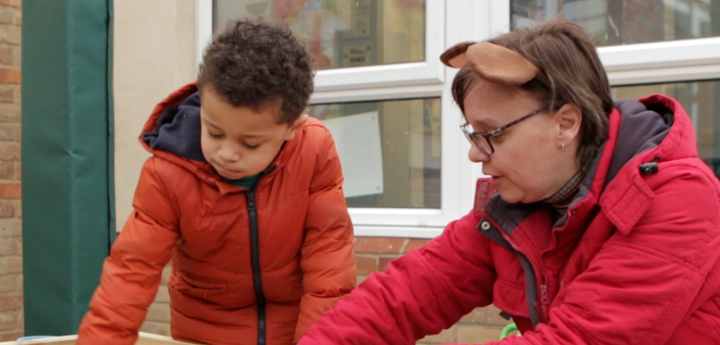 Young boy and teacher playing with a sand pit